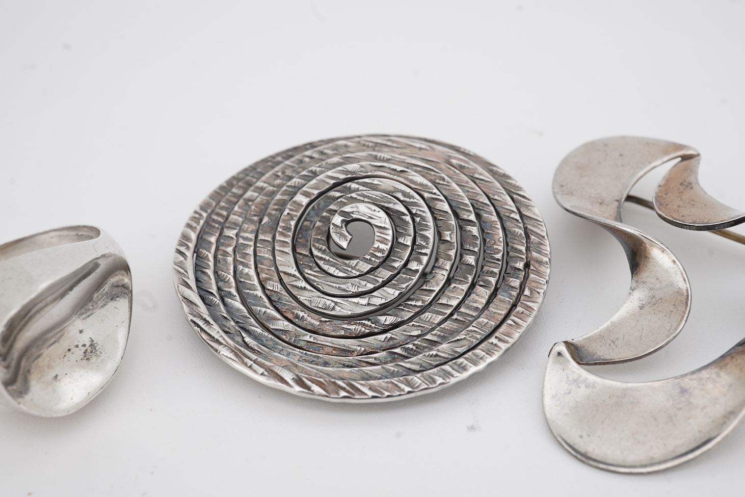 A mid to late 20th century Danish sterling tri-form brooch and a 925S ring by by Carl Ove Frydensberg, brooch, 43mm and a 1970's Finnish 925 circular brooch, by Kuppittaan Kulta, Turku, diameter 36mm.